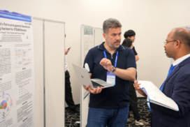 Two ICCCI 2026 attendees discuss a research poster while one presents from a laptop
